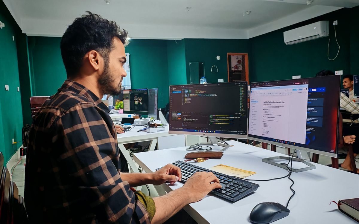 Developer working at a dual-monitor setup in a modern office