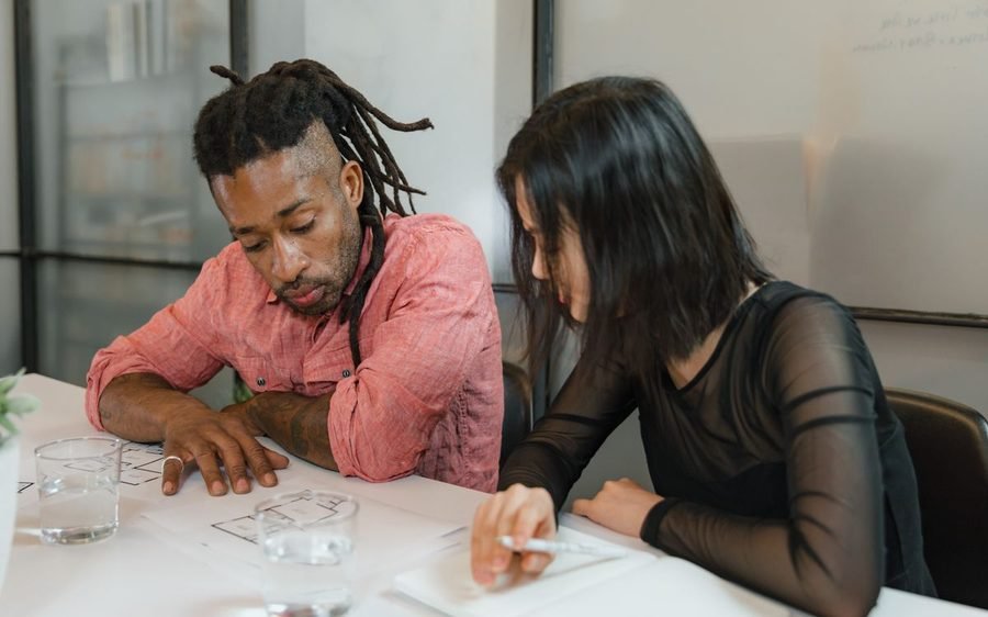Two colleagues working through project notes together at a desk